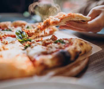Three firends together eating pizza in a cafe